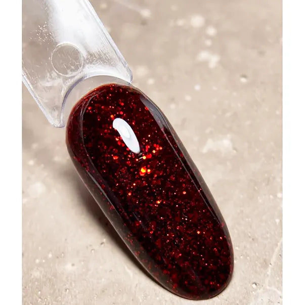 Red glittery nail polish on a textured beige background