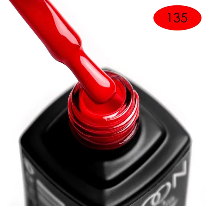 Red nail polish being applied to a black bottle with a visible brand name.