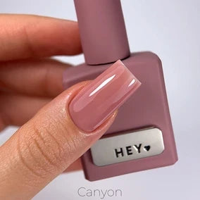 HEYLOVE Tónovací báze Canyon 15 ml – ruka s lesklou starorůžovou nude manikúrou drží lahvičku