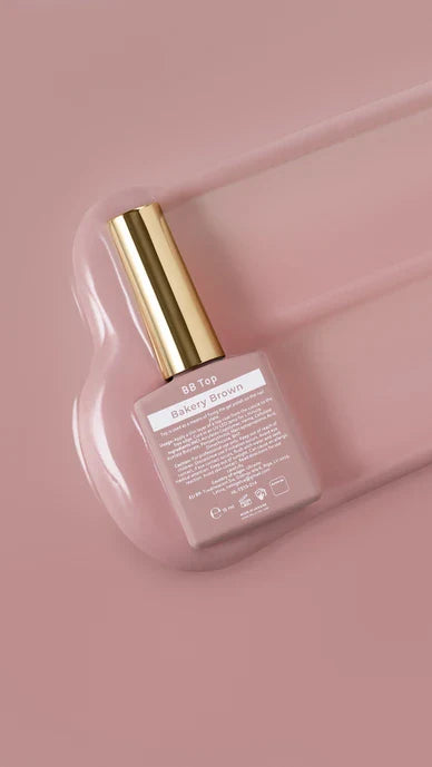 Pink nail polish bottle with gold cap on a pink background