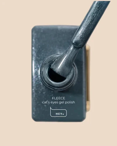 Cat's eyes gel polish with applicator on a beige background