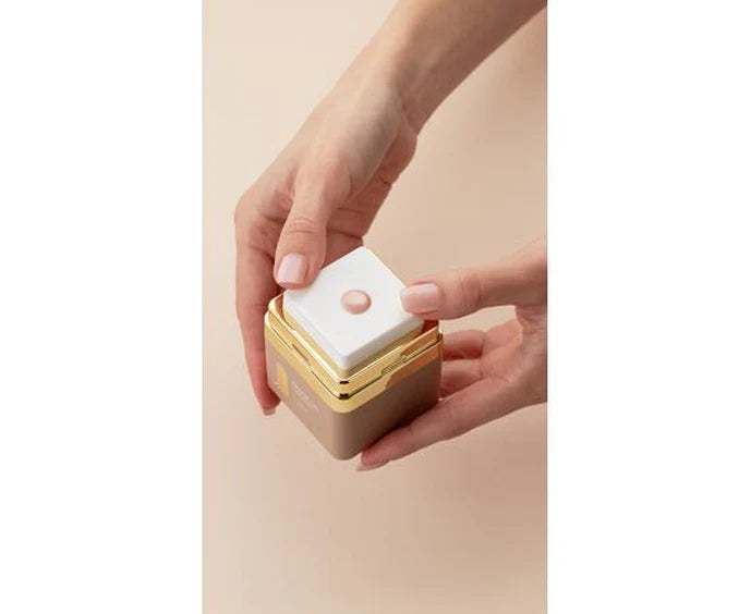 Hand holding HEYLOVE Frame Gel with a white top against a beige background