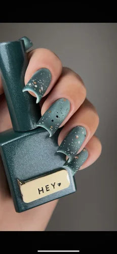 Teal nail polish bottle with 'HEY' label held by a hand with matching teal nails.